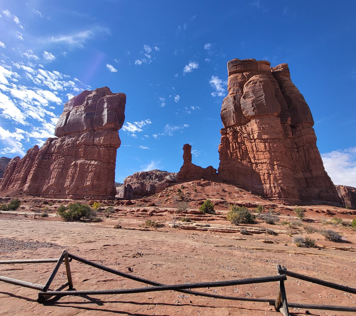 Giant rock formation in Moab, with a small wooden fence in foreground
