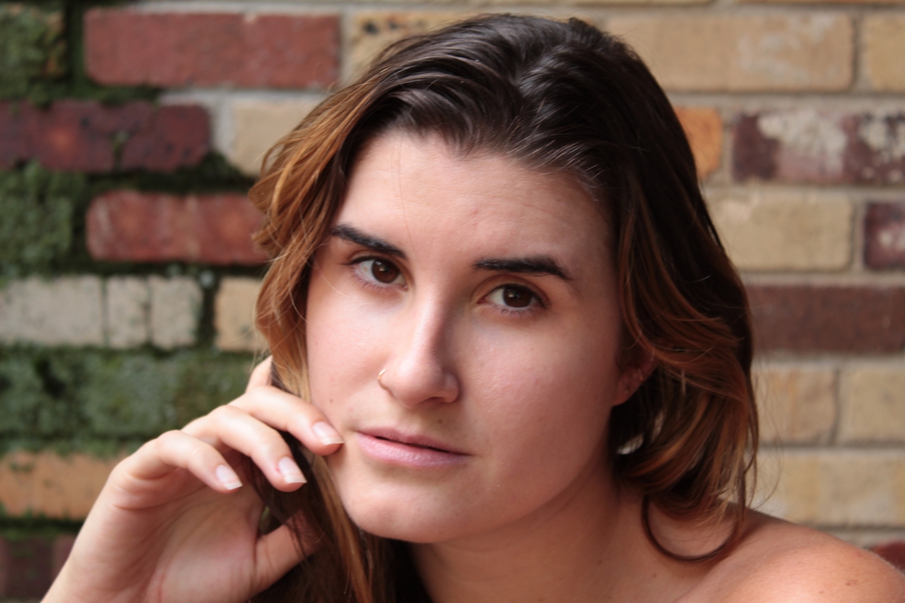 female head shot in front of a brick wall