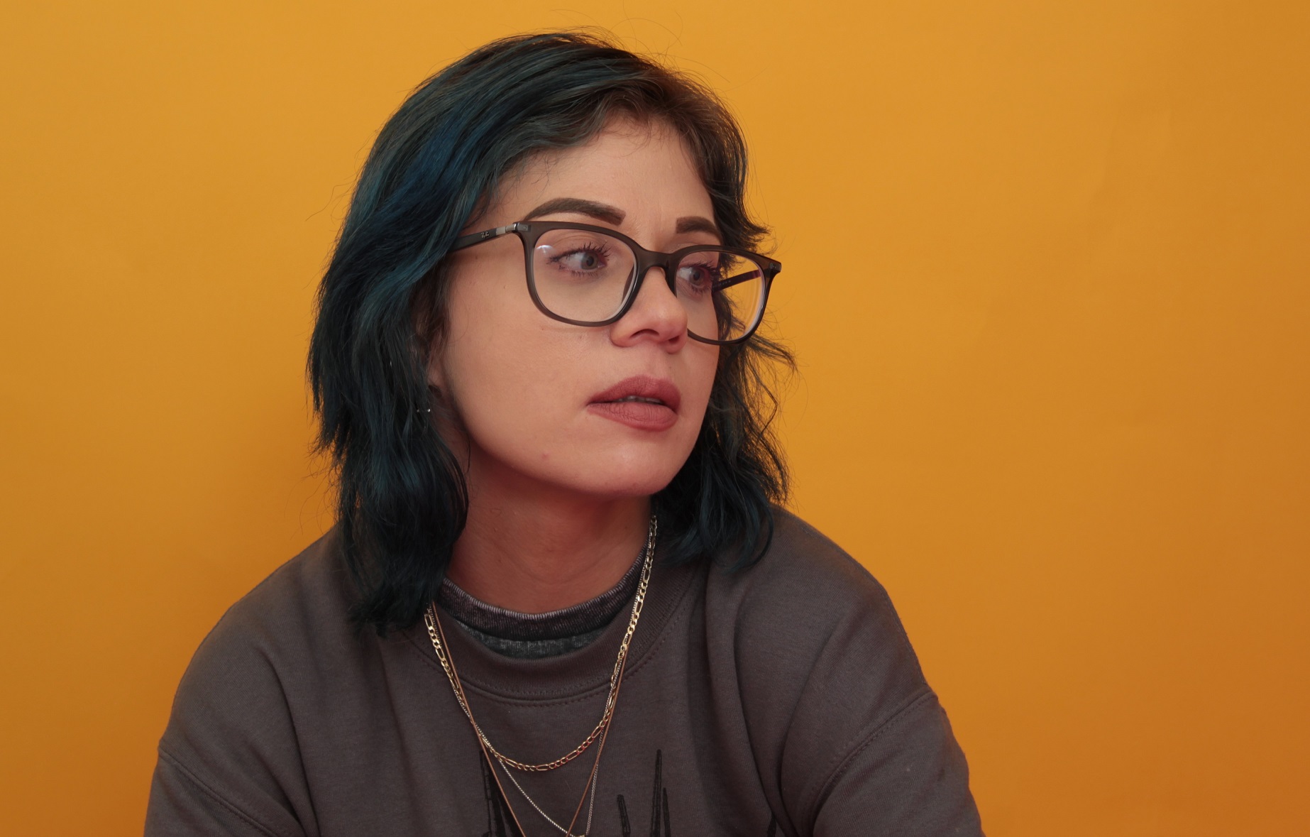 Headshot of woman wearing glasses. Yellow background